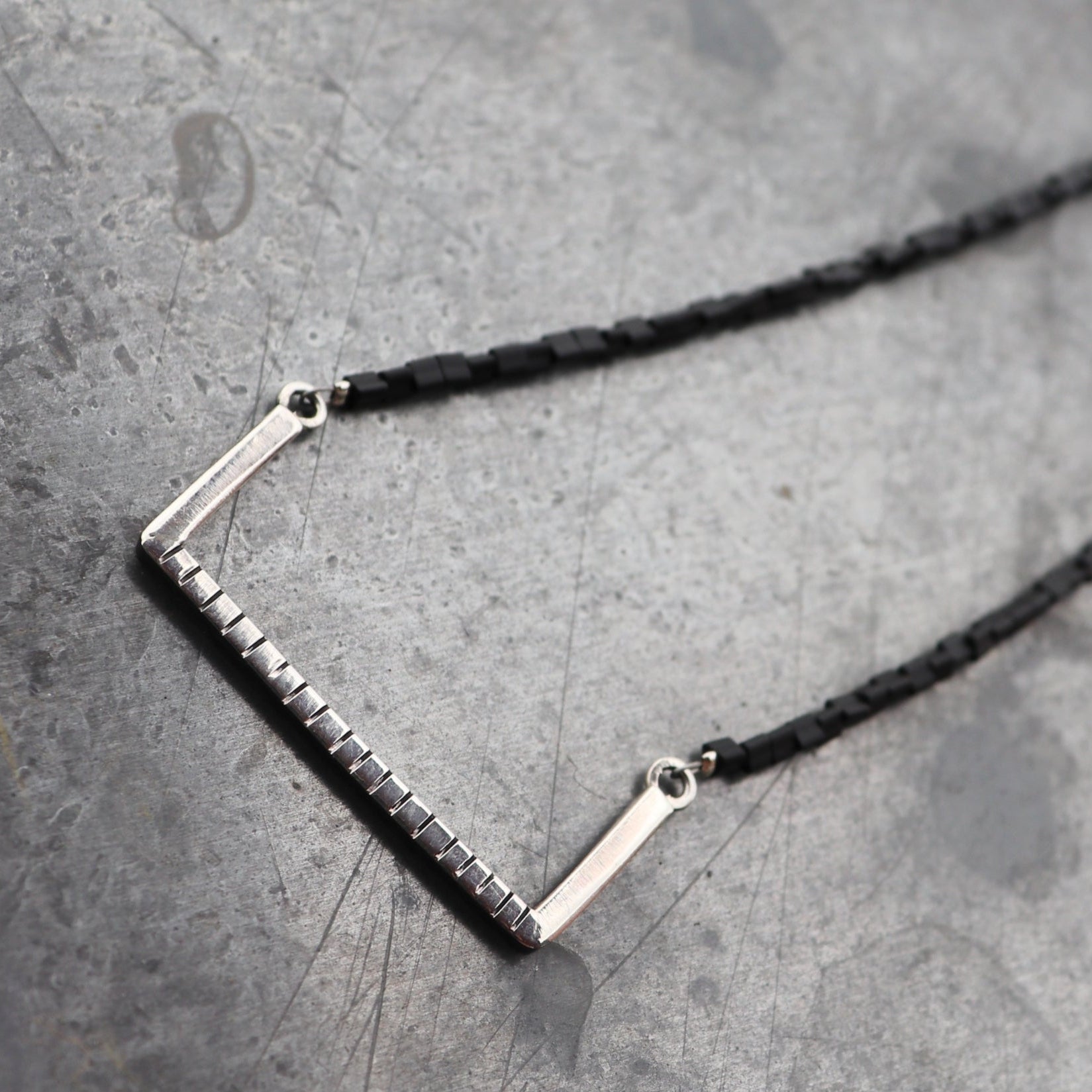 Handcrafted minimalist silver necklace "Between the Lines" with glass triangle beads, made from recycled silver. By ZiZou Nakit.