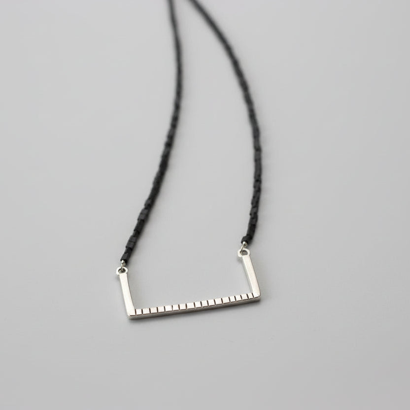 Handcrafted minimalist silver necklace "Between the Lines" with glass triangle beads, made from recycled silver. By ZiZou Nakit.