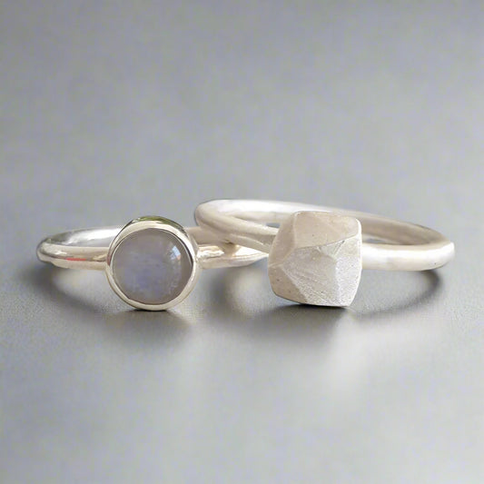 Two silver rings with moonstone on a textured surface