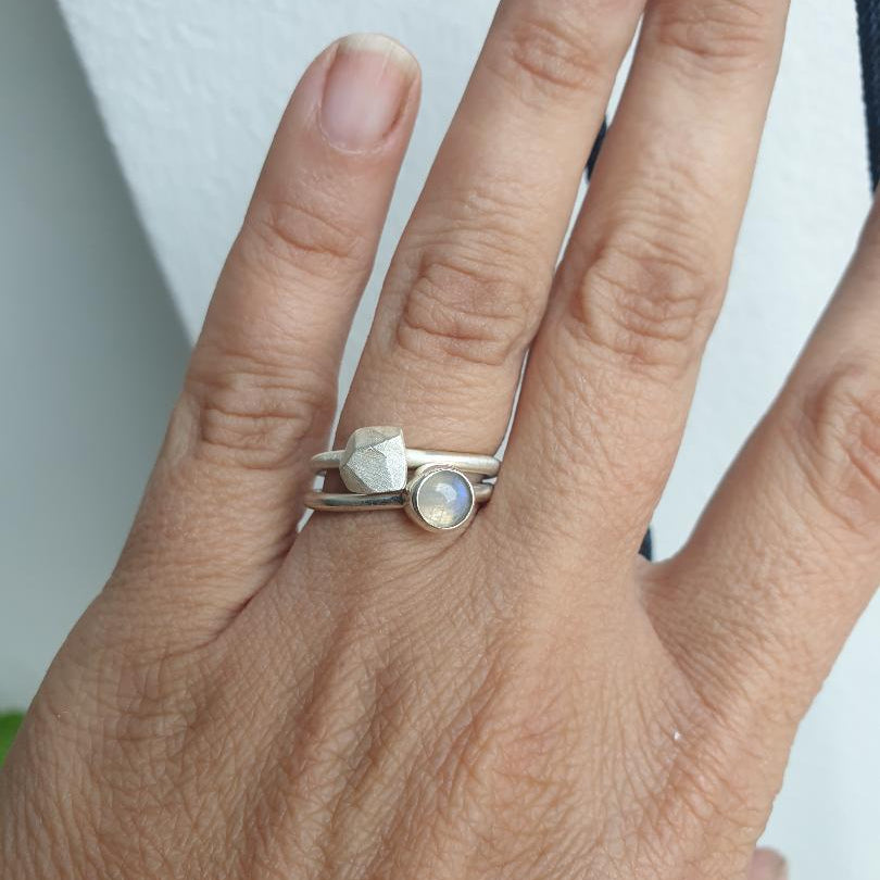 Hand wearing a silver ring with a gemstone on a neutral background moonstone 